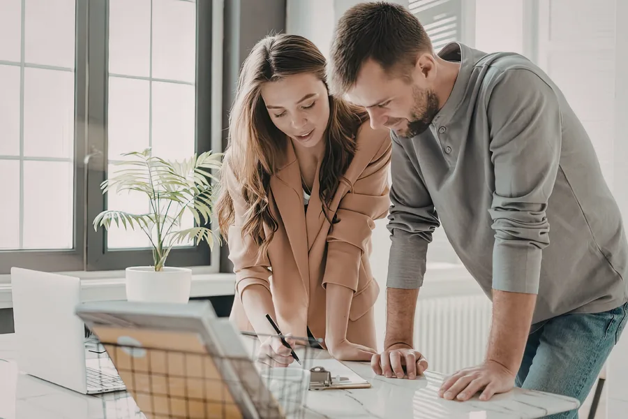 Two colleagues reviewing project documents together at a desk